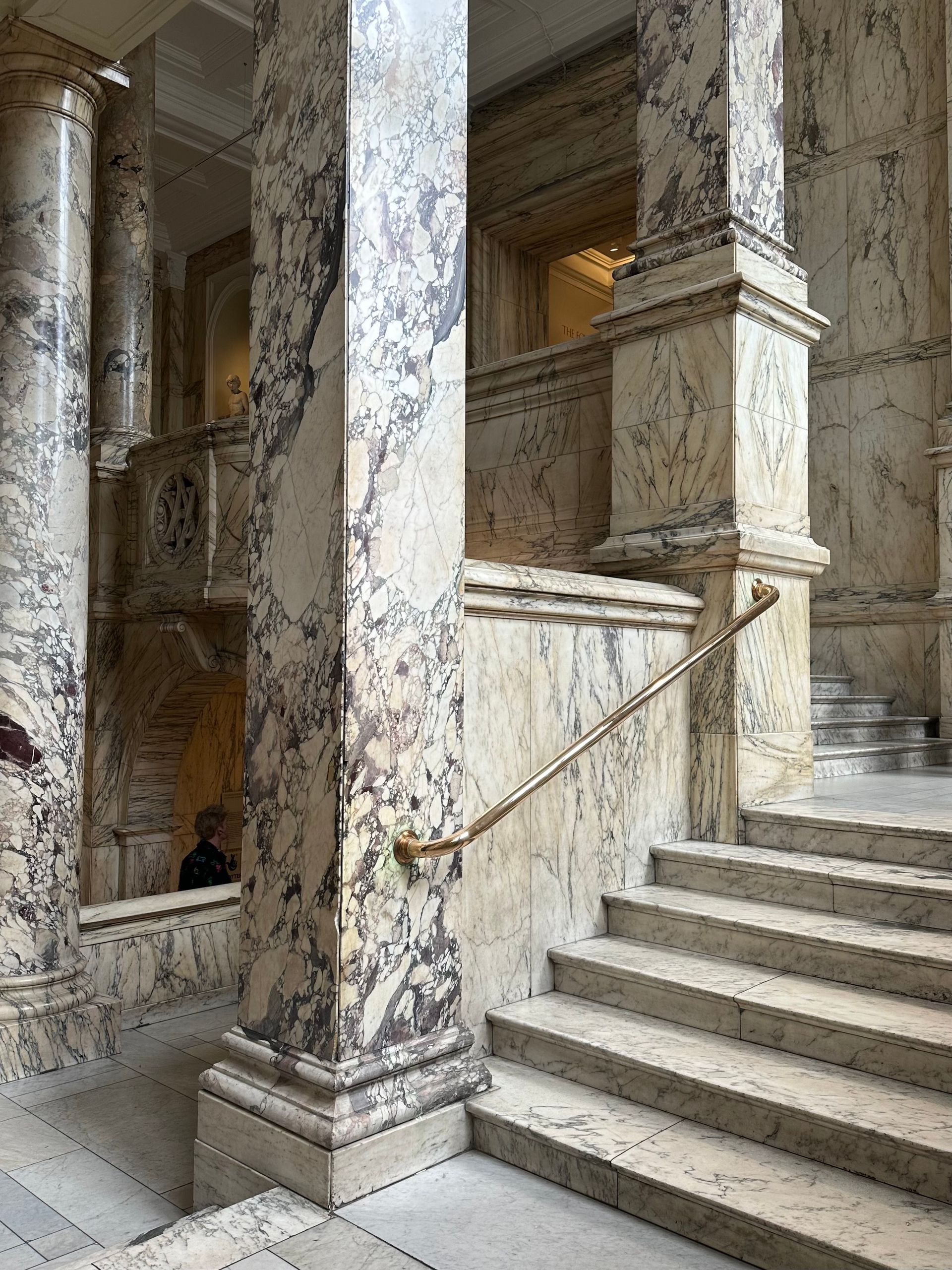 Marble pilasters and a brass handrail in a grand stair hall